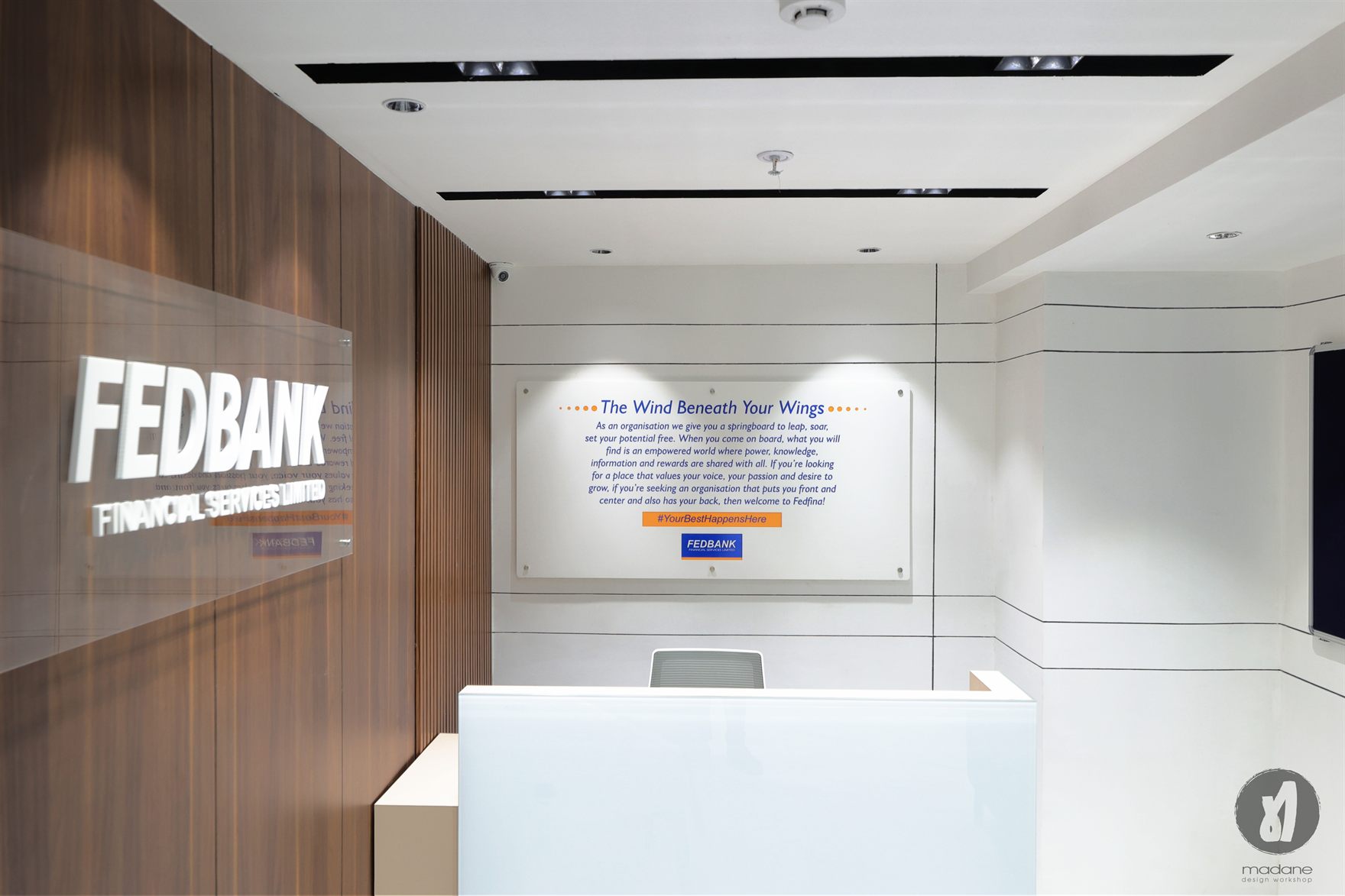 Reception with dimensional white FEDBANK Financial Services lettering on a walnut wall beside a back-lit brand statement panel